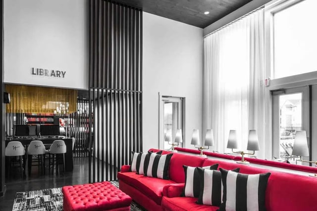 Red sofa black striped pillows library area living room at The Holly in Lubbock Student Accommodation