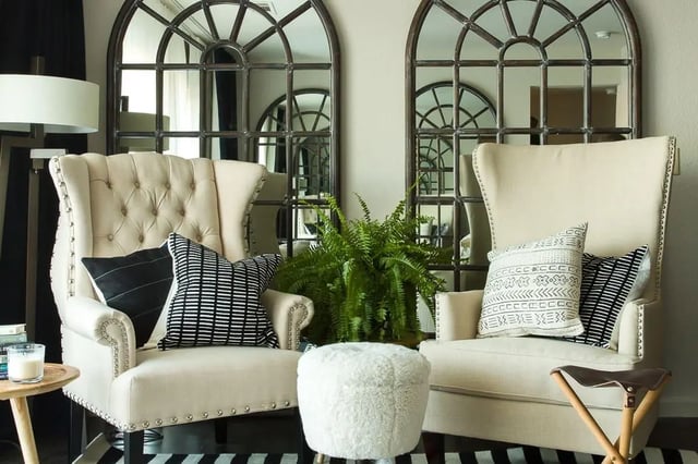 Two wingback chairs fluffy ottoman large mirrors living area at The Holly in Lubbock Student Accommodation