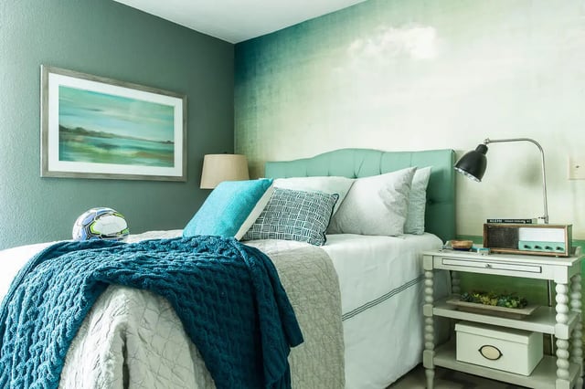 Bed with blue throw pillows and artwork bedroom at The Holly in Lubbock Student Accommodation