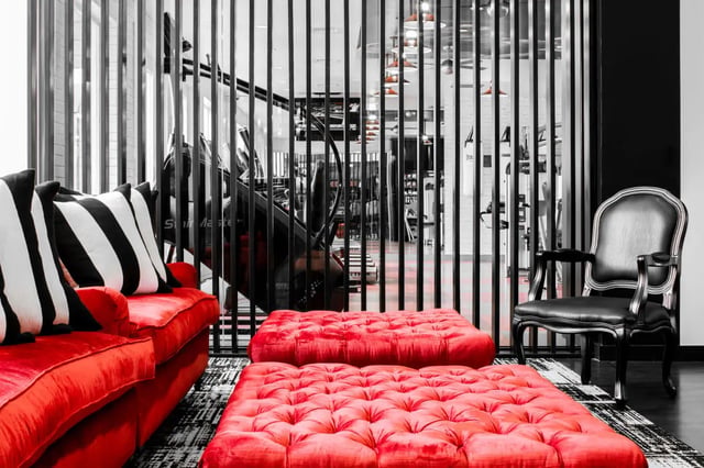 Red sofa striped cushions ottomans black chair living area at The Holly in Lubbock Student Accommodation