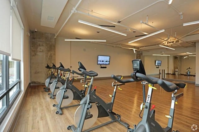 Row of spin bikes and screen fitness center at The Finmore at 241 in Boone Student Accommodation