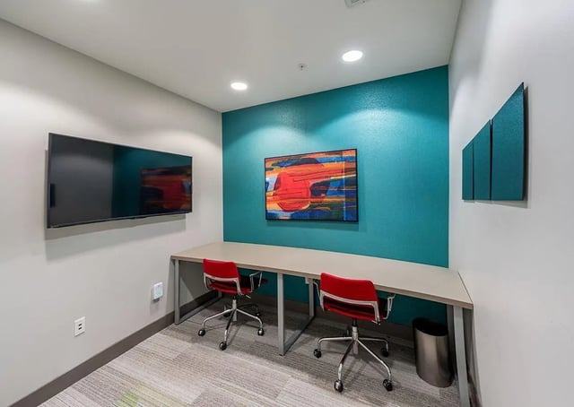 Two red chairs at long desk with wall television study area at The Avenue Indianapolis in Indianapolis Student Accommodation
