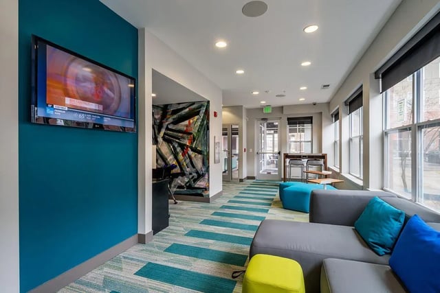 Modern living room with teal wall and sectional sofa. at The Avenue Indianapolis in Indianapolis Student Accommodation