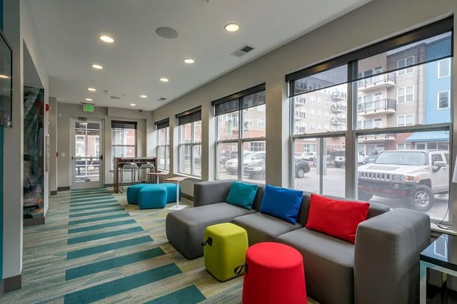 Modern lounge area with gray sectional sofa and colorful ottomans Living room at The Avenue Indianapolis in Indianapolis Student Accommodation