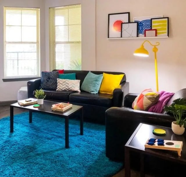 Black sofas blue rug coffee table living room at Lark Baton Rouge in Baton Rouge Student Accommodation