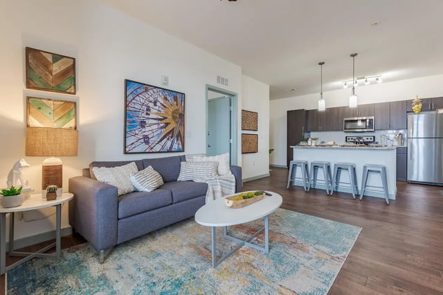 Gray sofa kitchen island and stainless steel appliances living room at Lark Syracuse in Syracuse Student Accommodation