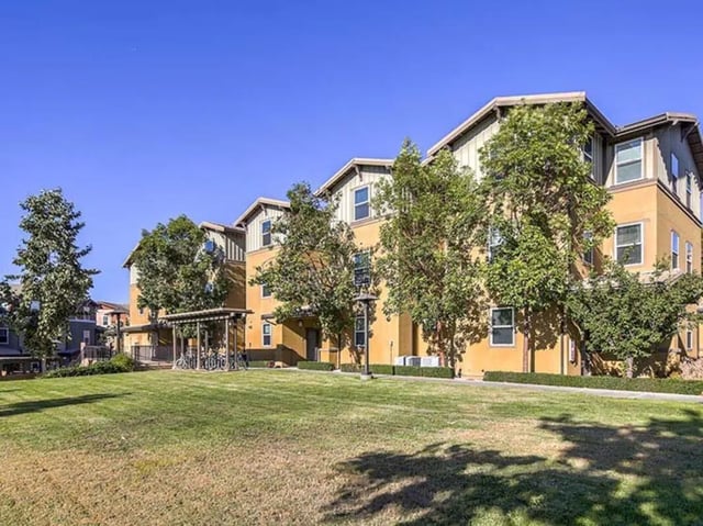 Orange buildings with trees and bicycles exterior at Camino del Sol in Irvine Student Accommodation