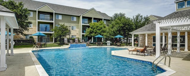 Pool umbrellas chairs building exterior living area at Aggie Station in Bryan Student Accommodation