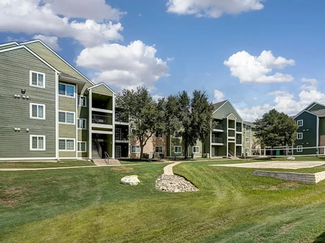 Apartment buildings with grass and volleyball court exterior at Aggie Station in Bryan Student Accommodation