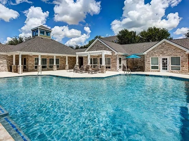 Pool with lounge chairs and umbrella exterior at Aggie Station in Bryan Student Accommodation