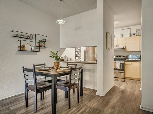 Dining table with chairs and shelves then kitchen at Aggie Station in Bryan Student Accommodation