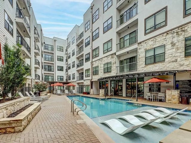 Modern apartment complex with pool and lounge chairs exterior at Crest at Pearl in Austin Student Accommodation