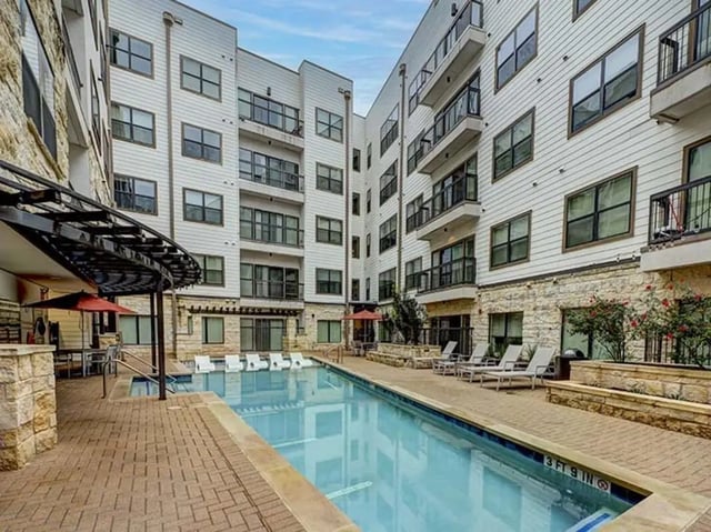 Apartment complex with pool lounge chairs and umbrellas exterior at Crest at Pearl in Austin Student Accommodation