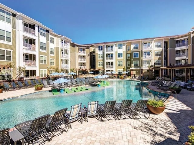 Apartment buildings surrounding a large swimming pool with lounge chairs exterior at 160 Ross in Auburn Student Accommodation