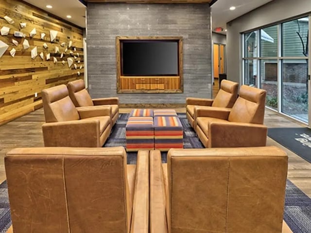 Leather chairs striped ottomans and TV living room at 160 Ross in Auburn Student Accommodation