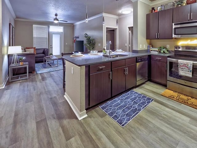 Kitchen island with sink and cabinets living room visible kitchen at 160 Ross in Auburn Student Accommodation