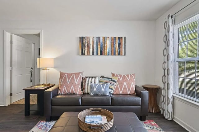 Dark leather sofa with patterned pillows living room at The Grove at Waco in Waco Student Accommodation