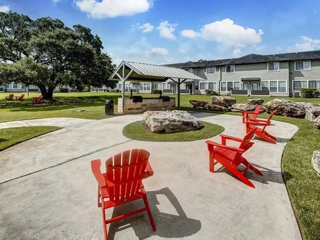Red chairs grilling station large tree exterior at Bishops Square in San Marcos Student Accommodation