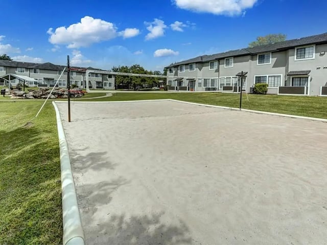 Sandy volleyball court with apartment buildings exterior at Bishops Square in San Marcos Student Accommodation