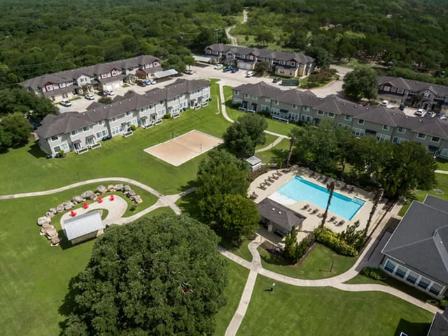 Apartment buildings pool volleyball court exterior at Bishops Square in San Marcos Student Accommodation