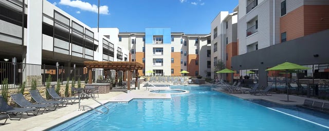 Swimming pool lounge chairs umbrellas and apartments exterior at Campus Edge on UTA Boulevard in Arlington Student Accommodation
