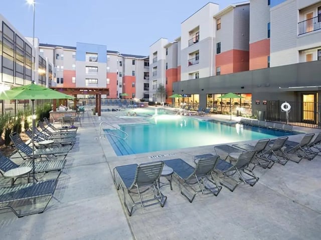 Pool lounge chairs umbrellas and buildings exterior at Campus Edge on UTA Boulevard in Arlington Student Accommodation
