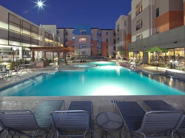 Pool lounge chairs and swimming pool exterior at Campus Edge on UTA Boulevard in Arlington Student Accommodation