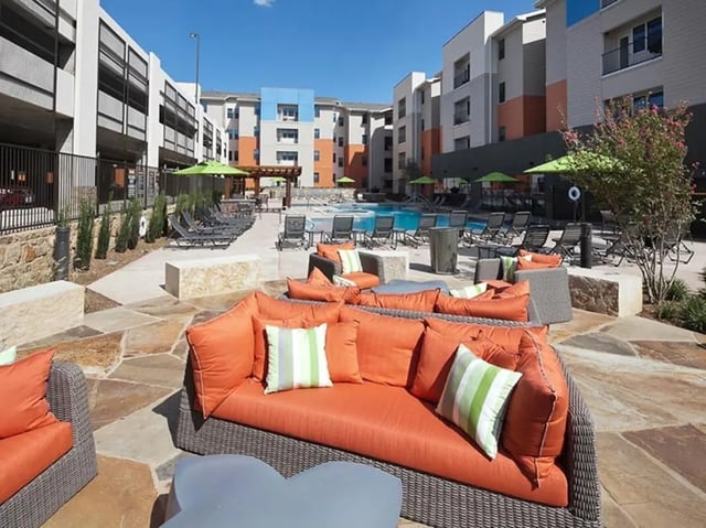 Orange sofa by pool and lounge chairs exterior at Campus Edge on UTA Boulevard in Arlington Student Accommodation