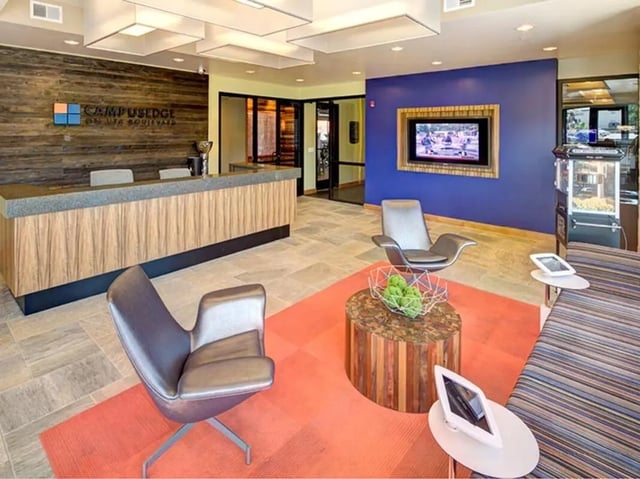 Reception desk chairs TV and coffee table lounge at Campus Edge on UTA Boulevard in Arlington Student Accommodation