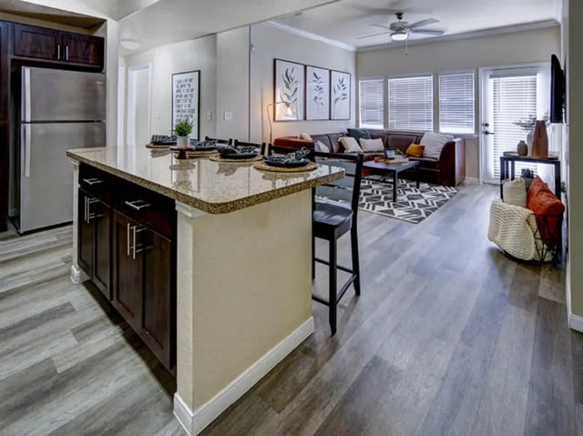 Kitchen island with chairs and living room living room at Campus Edge on UTA Boulevard in Arlington Student Accommodation
