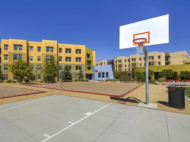 Basketball hoop volleyball court and apartment buildings exterior at Casas del Rio in Albuquerque Student Accommodation