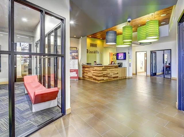 Red chaise lounge reception desk green pendant lamps lobby at Casas del Rio in Albuquerque Student Accommodation
