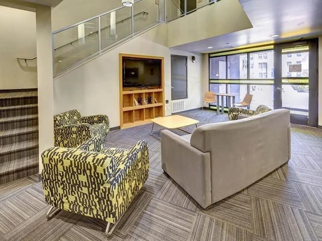 Sofa chairs table television stairs common area at Casas del Rio in Albuquerque Student Accommodation
