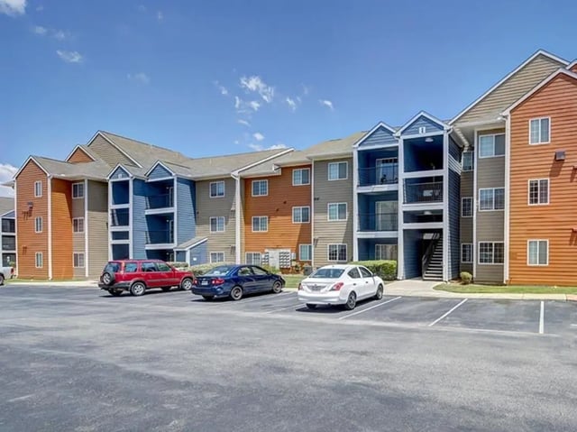 Apartment building with cars parked exterior at Campus Edge on UTSA Boulevard in San Antonio Student Accommodation