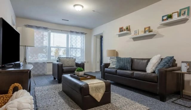 Leather sofa and armchair with ottoman living room at The Reserve at Mt. Pleasant in Mount Pleasant Student Accommodation