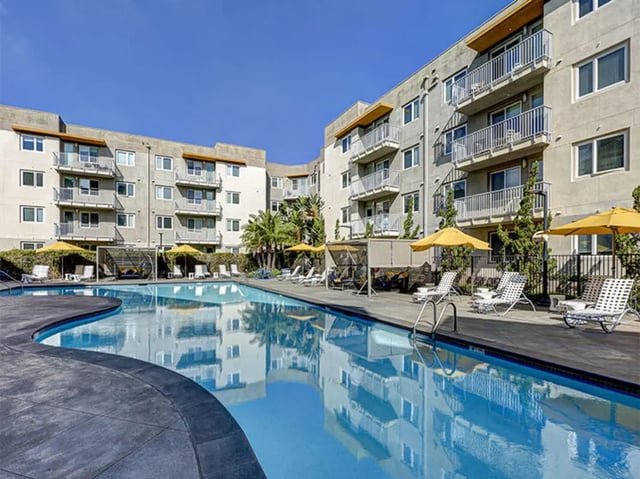 Apartment buildings surrounding pool and lounge chairs exterior at Currie Hall in Los Angeles Student Accommodation