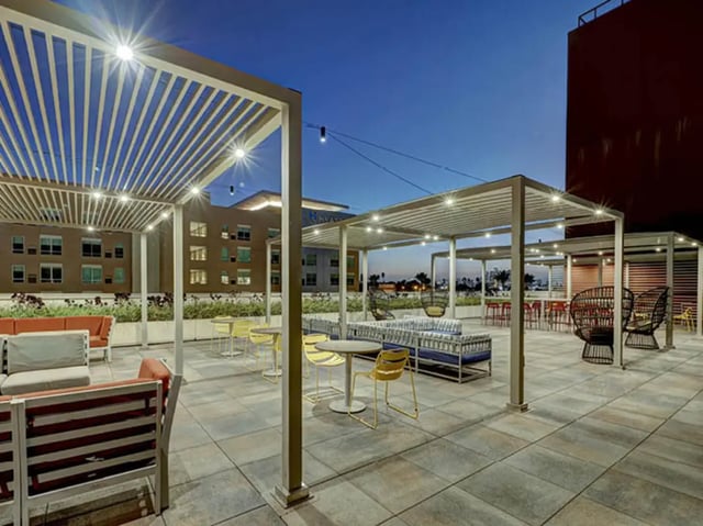 Outdoor seating lounge area with tables chairs exterior at Currie Hall in Los Angeles Student Accommodation