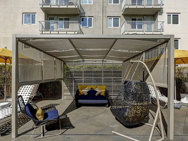 Outdoor lounge with seating and hanging chair exterior at Currie Hall in Los Angeles Student Accommodation