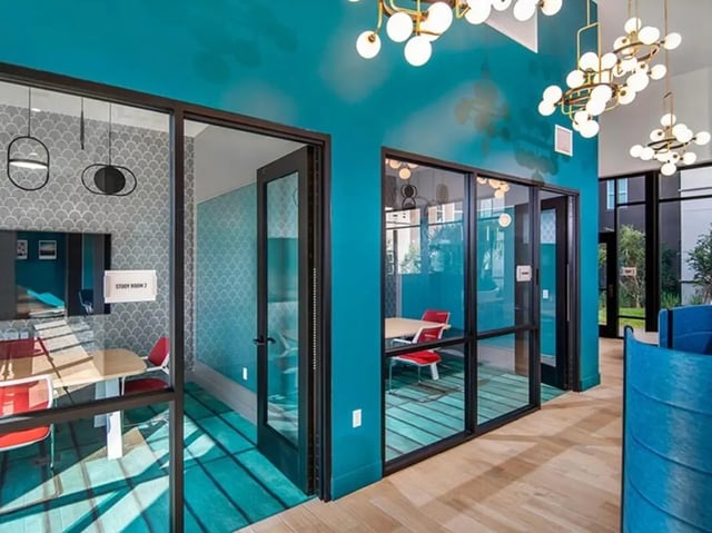 Modern study rooms with tables chairs and teal walls Study area at Currie Hall in Los Angeles Student Accommodation