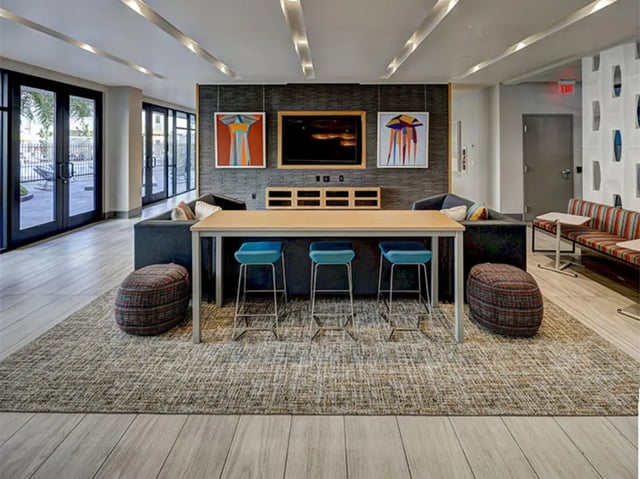 Large table with blue stools and artwork Living room at Currie Hall in Los Angeles Student Accommodation