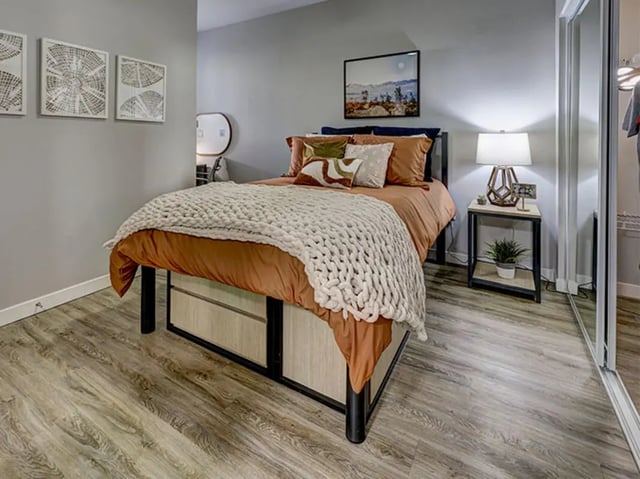 Bed with knit blanket bedside table lamp bedroom at Currie Hall in Los Angeles Student Accommodation