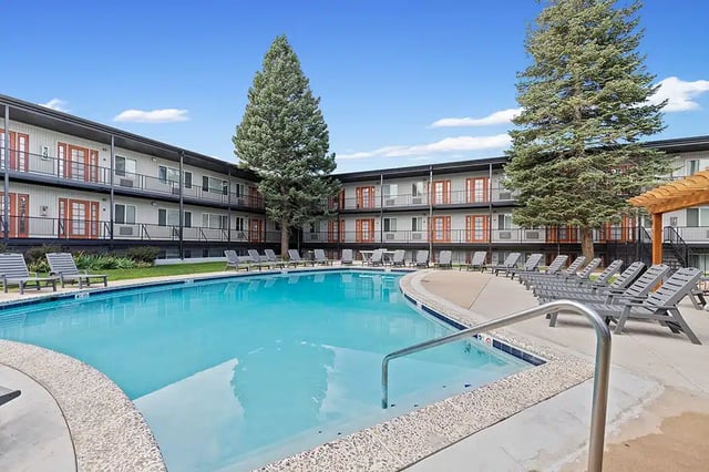 Pool lounge chairs building exterior and trees outdoor area at The Lodge
