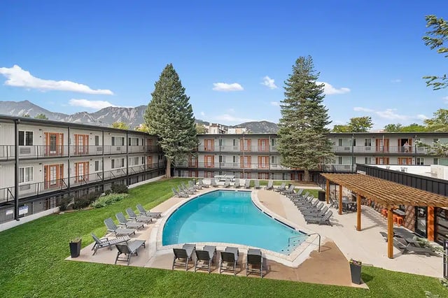 Apartment building with pool and lounge chairs exterior at The Lodge
