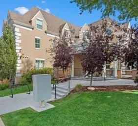 Tan apartment building entrance with trees exterior at The Lodge