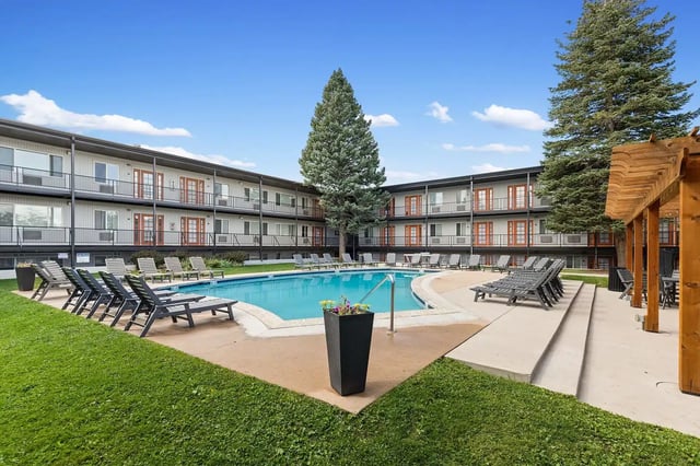 Apartment building pool lounge chairs green grass exterior at The Lodge