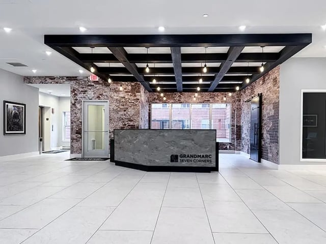 Reception desk with exposed brick and overhead lights lobby at GrandMarc Seven Corners in Minneapolis Student Accommodation