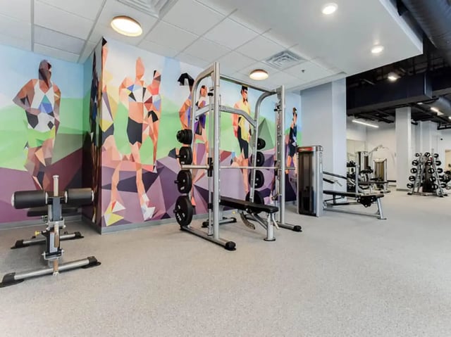 Gym equipment with colorful runner mural gym area at GrandMarc Seven Corners in Minneapolis Student Accommodation