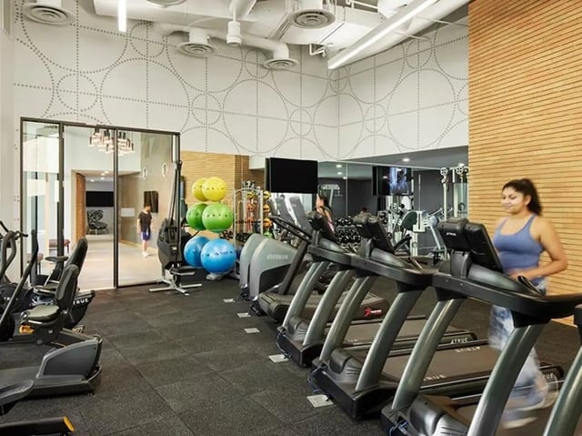 Treadmills exercise balls weights woman running gym. at North District in Riverside Student Accommodation