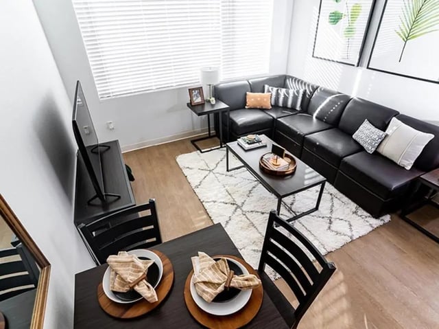 Black sectional sofa coffee table rug living room at North District in Riverside Student Accommodation