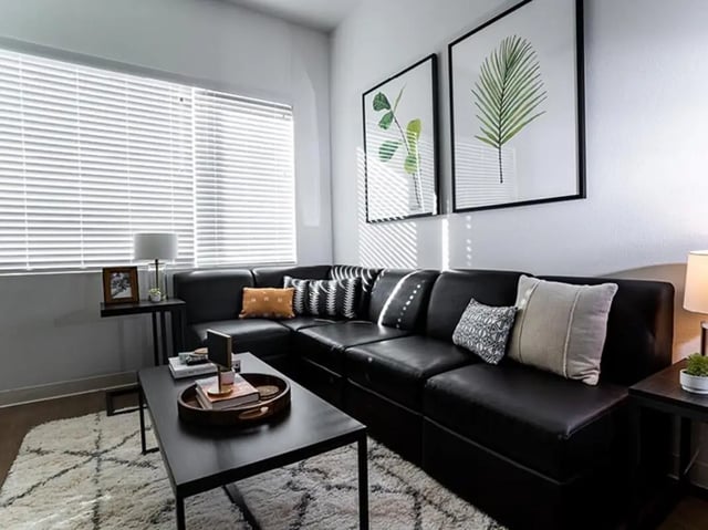 Black sectional sofa with pillows coffee table living room at North District in Riverside Student Accommodation